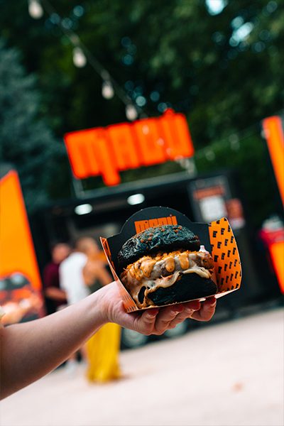 Hamburguesa en mano frente a un food truck